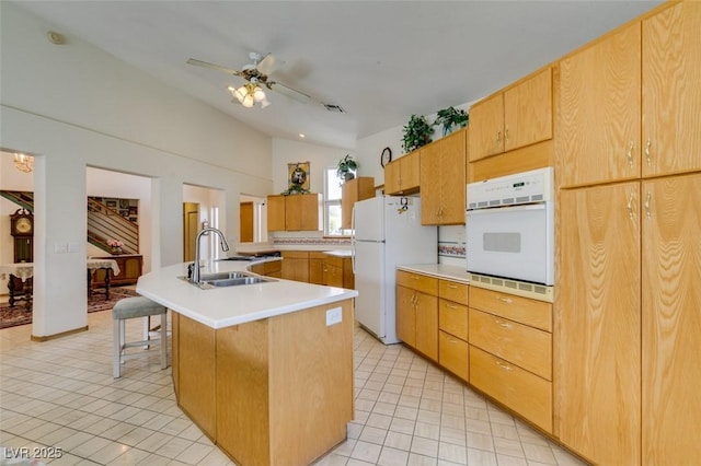 kitchen with a sink, white appliances, light countertops, lofted ceiling, and a center island with sink