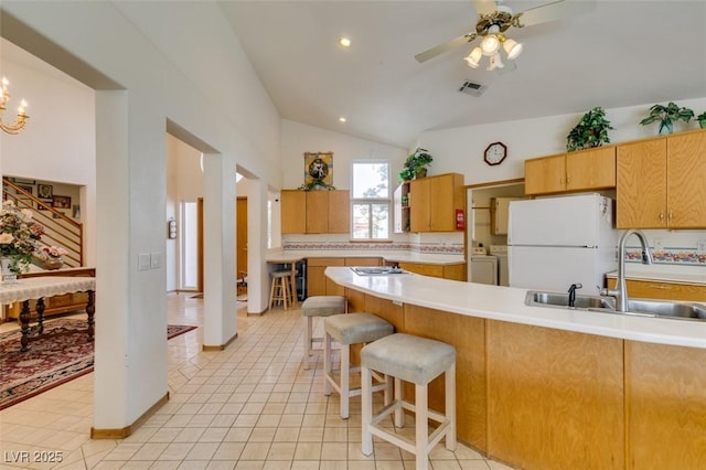 kitchen with visible vents, lofted ceiling, white appliances, light countertops, and a sink
