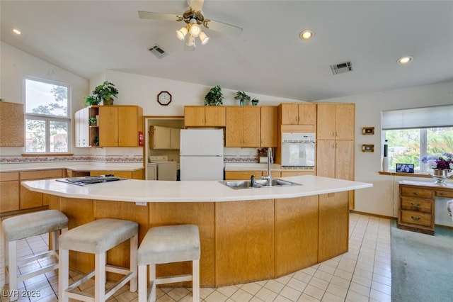 kitchen with white appliances, visible vents, a sink, and washing machine and clothes dryer