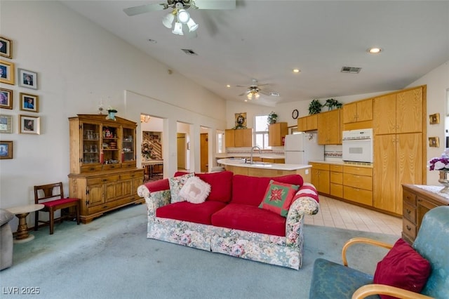 living room featuring ceiling fan, light carpet, vaulted ceiling, and visible vents