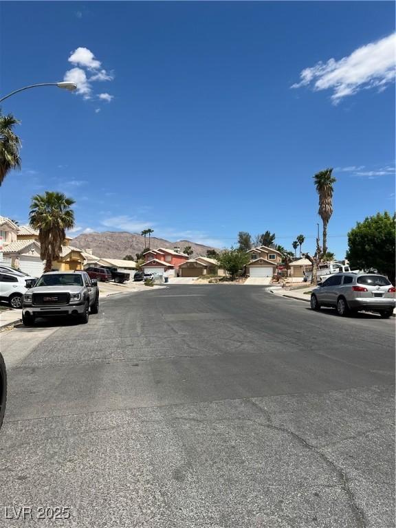 view of street featuring a residential view, sidewalks, curbs, and street lights