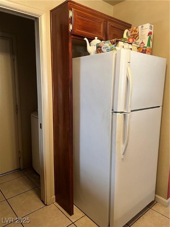 kitchen with light tile patterned floors and freestanding refrigerator