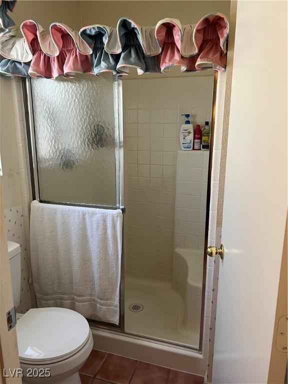 full bathroom featuring toilet, a shower stall, and tile patterned flooring