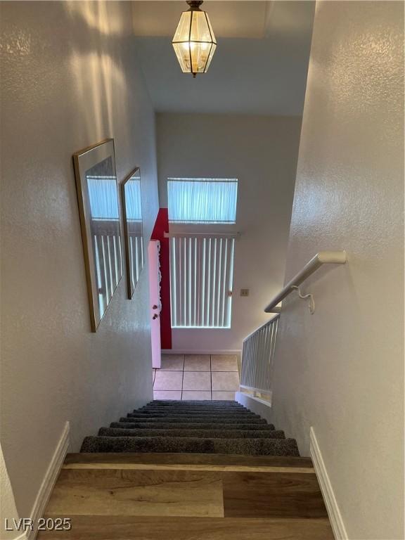 staircase featuring a textured wall and tile patterned floors