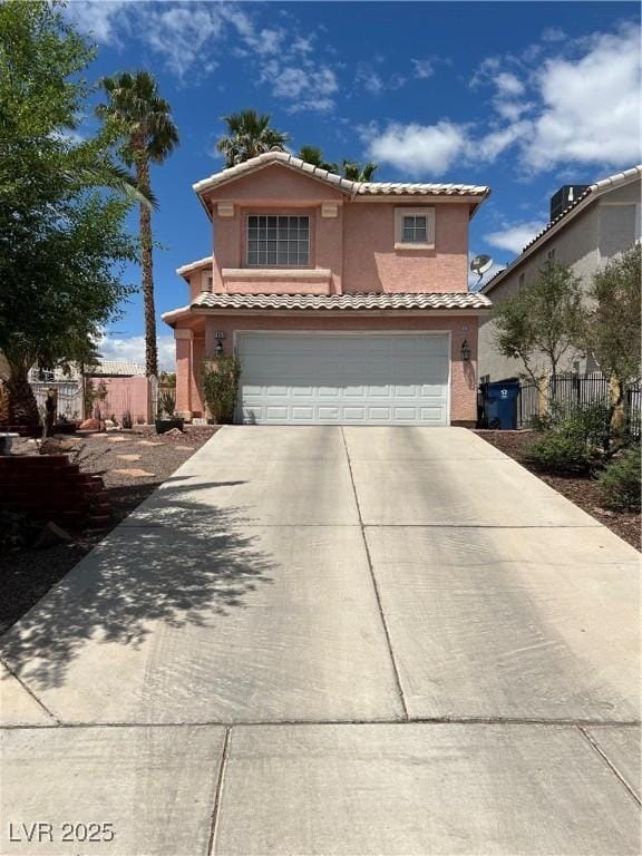 traditional-style home featuring fence, stucco siding, a tiled roof, concrete driveway, and an attached garage