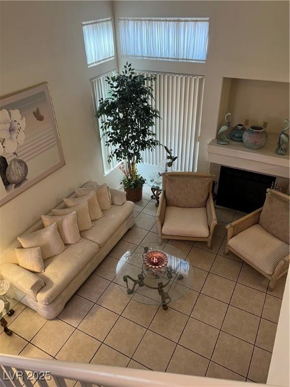 living area featuring a high ceiling, light tile patterned floors, and a fireplace