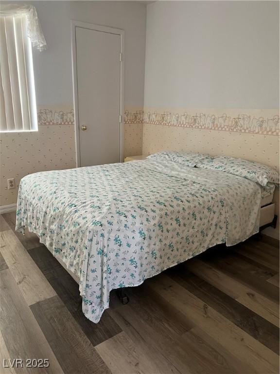 bedroom featuring wood finished floors and a wainscoted wall