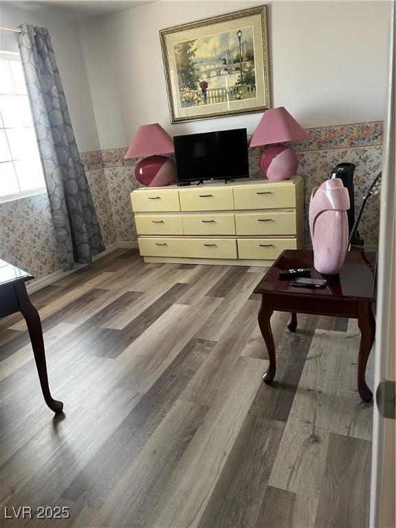 bedroom featuring a wainscoted wall, wallpapered walls, and wood finished floors