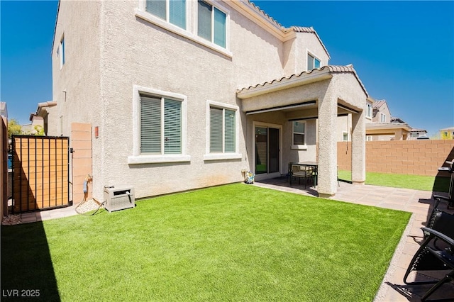 rear view of house with a yard, a patio, fence, and stucco siding