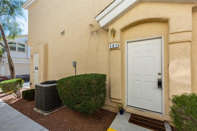 property entrance featuring central AC unit and stucco siding