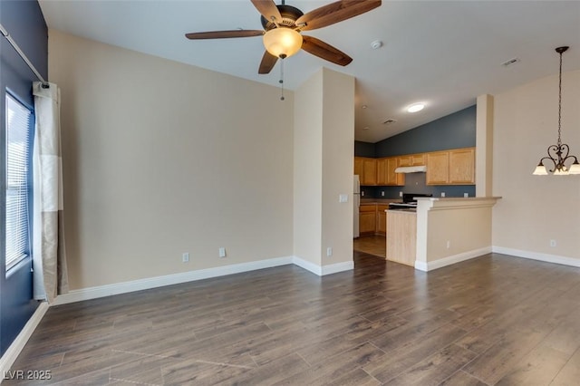 unfurnished living room with ceiling fan with notable chandelier, baseboards, vaulted ceiling, and dark wood-style floors