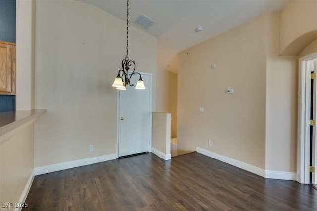 unfurnished dining area featuring visible vents, vaulted ceiling, dark wood finished floors, baseboards, and an inviting chandelier