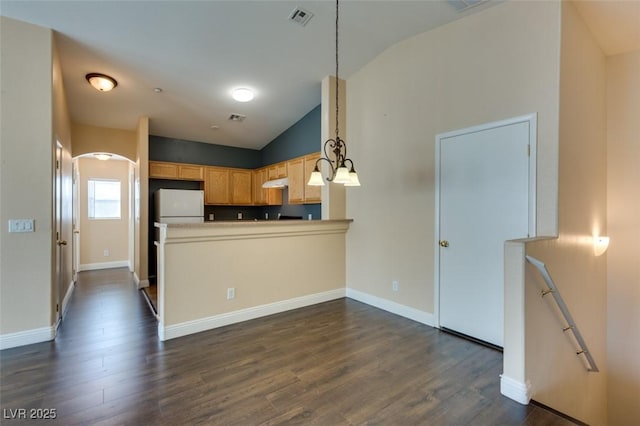 kitchen featuring visible vents, freestanding refrigerator, dark wood-type flooring, under cabinet range hood, and vaulted ceiling