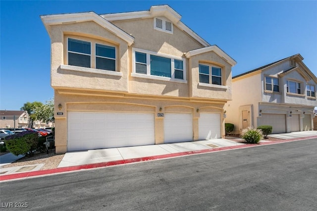 6576 Buster Brown Ave Unit 101, Las Vegas, NV 89122 - view of property featuring a garage, stucco siding, and driveway