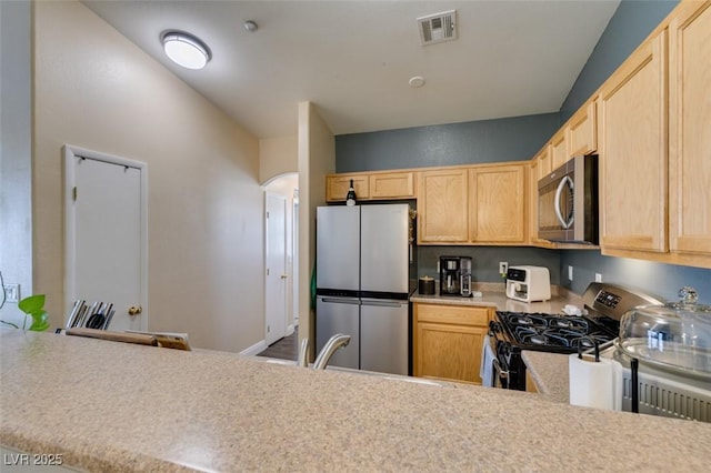 6576 Buster Brown Ave Unit 101, Las Vegas, NV 89122 - kitchen with stainless steel appliances, light brown cabinets, light countertops, a sink, and arched walkways
