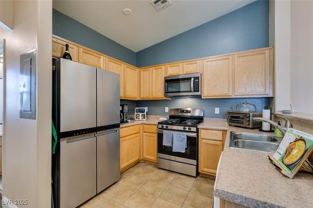 6576 Buster Brown Ave Unit 101, Las Vegas, NV 89122 - kitchen with stainless steel appliances, light brown cabinets, a sink, lofted ceiling, and light tile patterned flooring