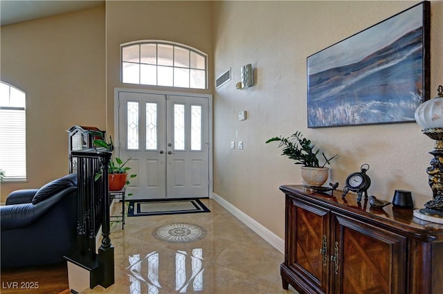 foyer entrance featuring baseboards, a high ceiling, and visible vents