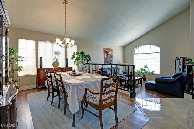 dining space with baseboards, a chandelier, wood finished floors, and vaulted ceiling