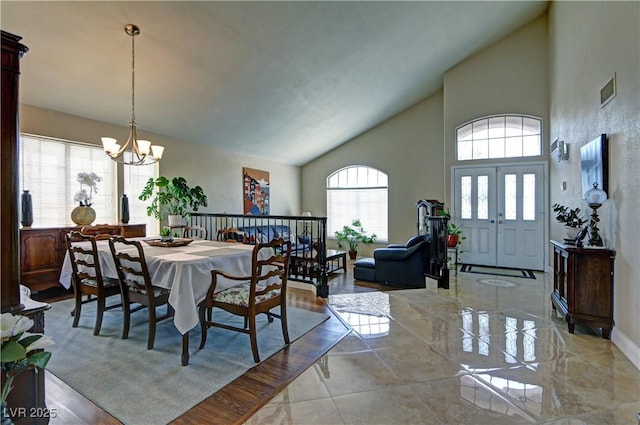 dining room featuring an inviting chandelier, high vaulted ceiling, and baseboards