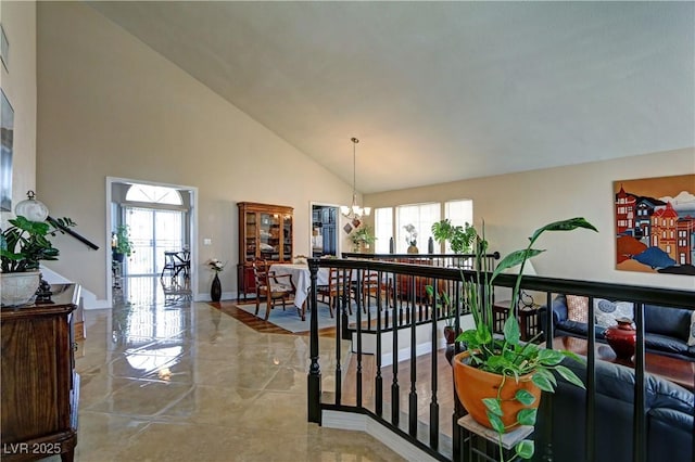 interior space featuring an inviting chandelier, baseboards, a healthy amount of sunlight, and high vaulted ceiling
