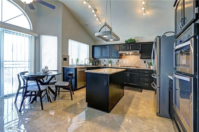 kitchen featuring appliances with stainless steel finishes, a sink, high vaulted ceiling, a ceiling fan, and a kitchen island
