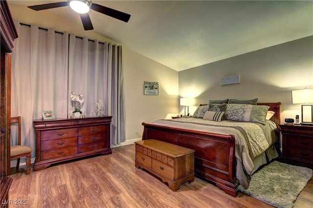 bedroom featuring ceiling fan, wood finished floors, and vaulted ceiling