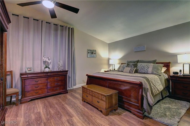 bedroom with a ceiling fan, wood finished floors, and vaulted ceiling