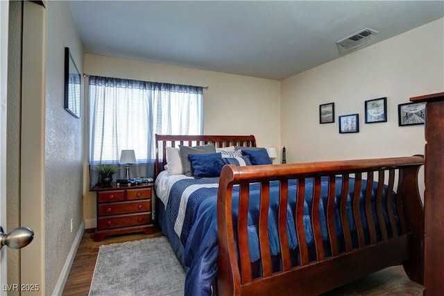 bedroom with baseboards, dark wood-type flooring, and visible vents