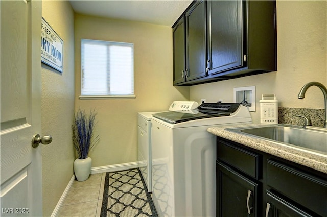 laundry area featuring light tile patterned flooring, baseboards, separate washer and dryer, a sink, and cabinet space