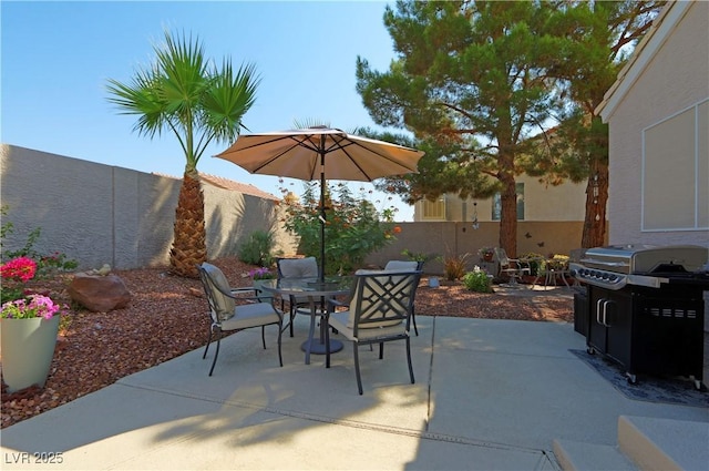 view of patio with area for grilling, outdoor dining space, and a fenced backyard