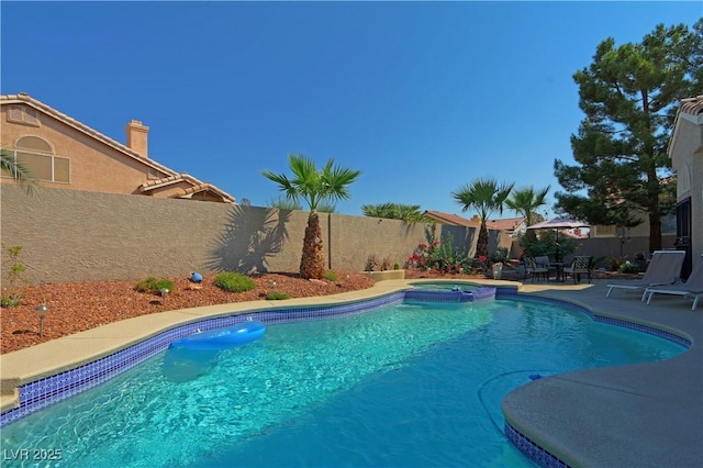 view of swimming pool with a fenced backyard, a pool with connected hot tub, and a patio area