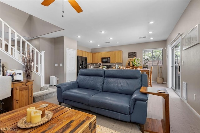 living room featuring stairway, recessed lighting, baseboards, a ceiling fan, and light wood-style floors