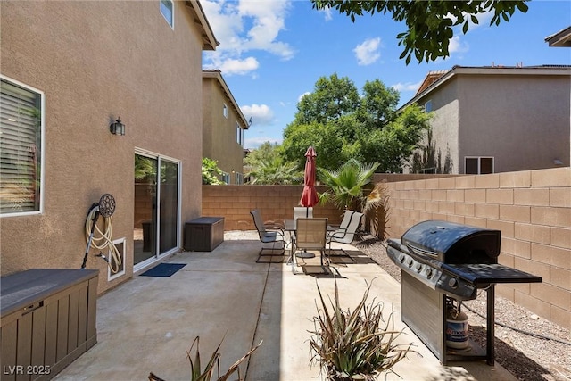 view of patio with a grill, fence, and outdoor dining space
