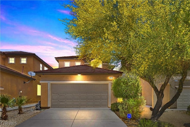view of front facade featuring driveway, stucco siding, and a garage