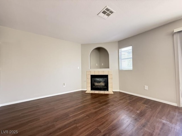 2105 William Holden Ct, Las Vegas, NV 89142 - unfurnished living room with visible vents, baseboards, dark wood-type flooring, and a tile fireplace