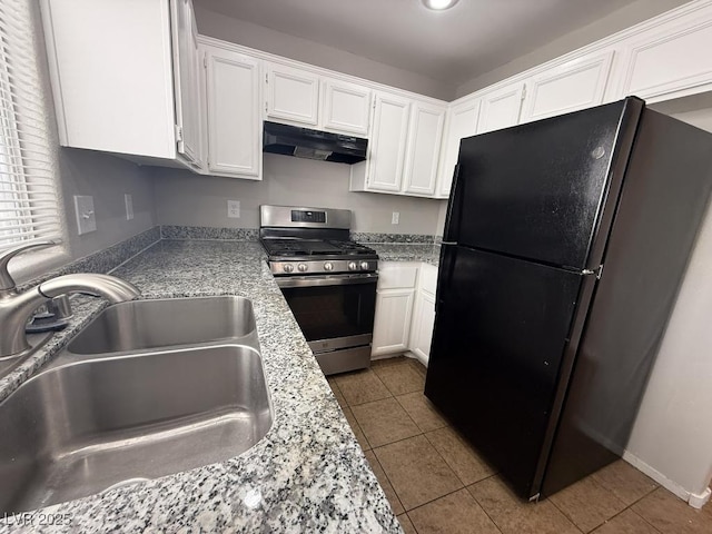 2105 William Holden Ct, Las Vegas, NV 89142 - kitchen with freestanding refrigerator, stainless steel gas stove, white cabinetry, under cabinet range hood, and a sink