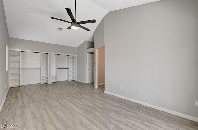 unfurnished bedroom with two closets, baseboards, visible vents, and light wood finished floors