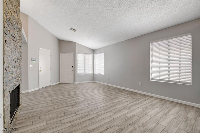 unfurnished living room with visible vents, lofted ceiling, baseboards, a textured ceiling, and light wood finished floors