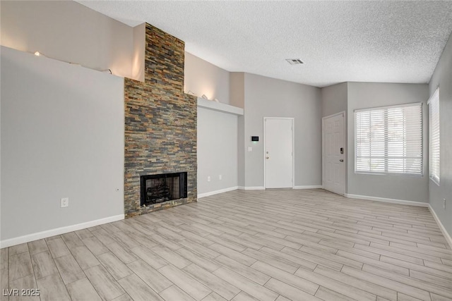 unfurnished living room with a fireplace, light wood-style flooring, a textured ceiling, and visible vents