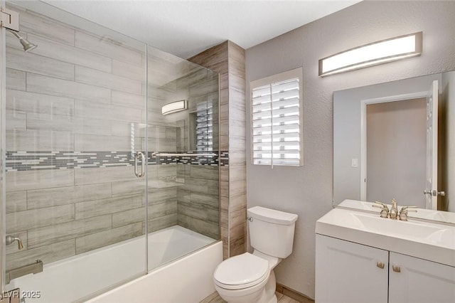 bathroom with toilet, combined bath / shower with glass door, and vanity