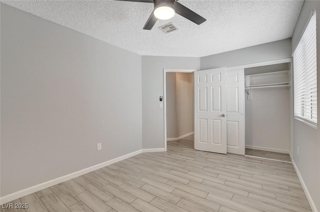 unfurnished bedroom featuring light wood-style floors, a textured ceiling, a ceiling fan, baseboards, and visible vents