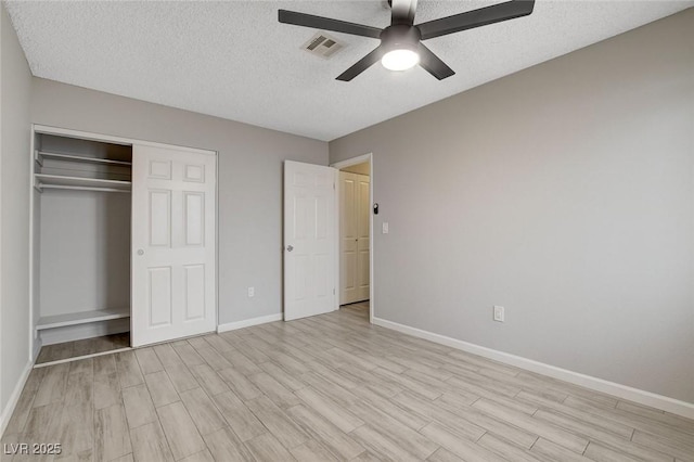 unfurnished bedroom featuring light wood finished floors, a textured ceiling, baseboards, visible vents, and a closet