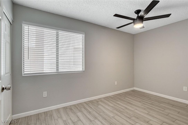 empty room with a textured ceiling, ceiling fan, plenty of natural light, and wood finished floors