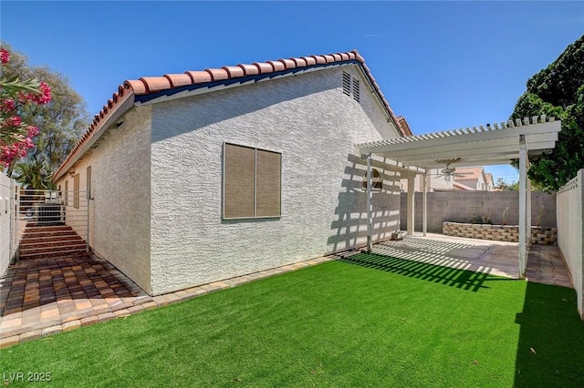 rear view of property with a pergola, a fenced backyard, stucco siding, a patio area, and a lawn