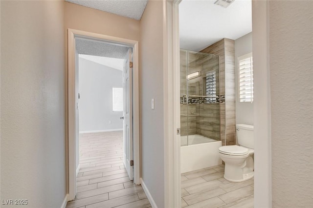 bathroom featuring plenty of natural light, enclosed tub / shower combo, toilet, and visible vents