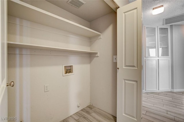clothes washing area with visible vents, laundry area, light wood-style floors, and hookup for a washing machine