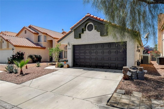 mediterranean / spanish house featuring a garage, stucco siding, concrete driveway, cooling unit, and a tiled roof