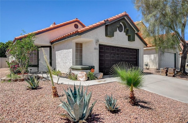view of front facade with a tiled roof, an attached garage, concrete driveway, and stucco siding