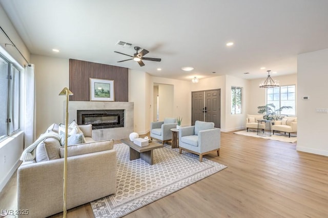 living area with visible vents, wood finished floors, baseboards, recessed lighting, and a high end fireplace