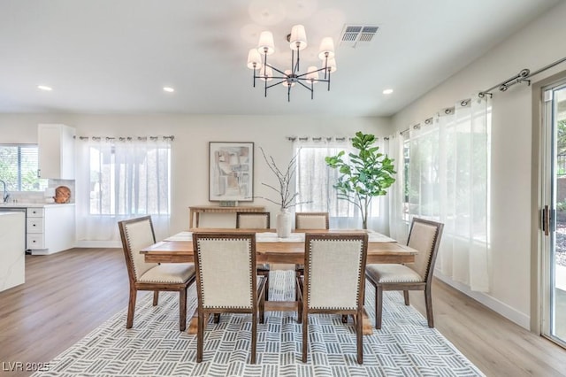 dining room with a chandelier, visible vents, a healthy amount of sunlight, and light wood-style floors